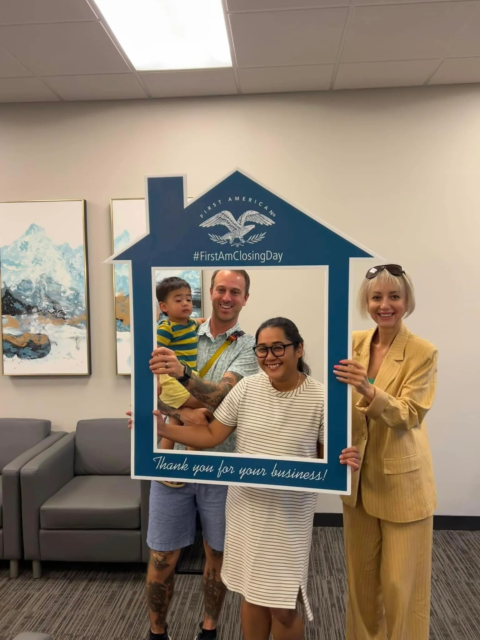 Young family with a toddler at their closing with Tamila Aspen, holding a First American "Thank you for your business" frame