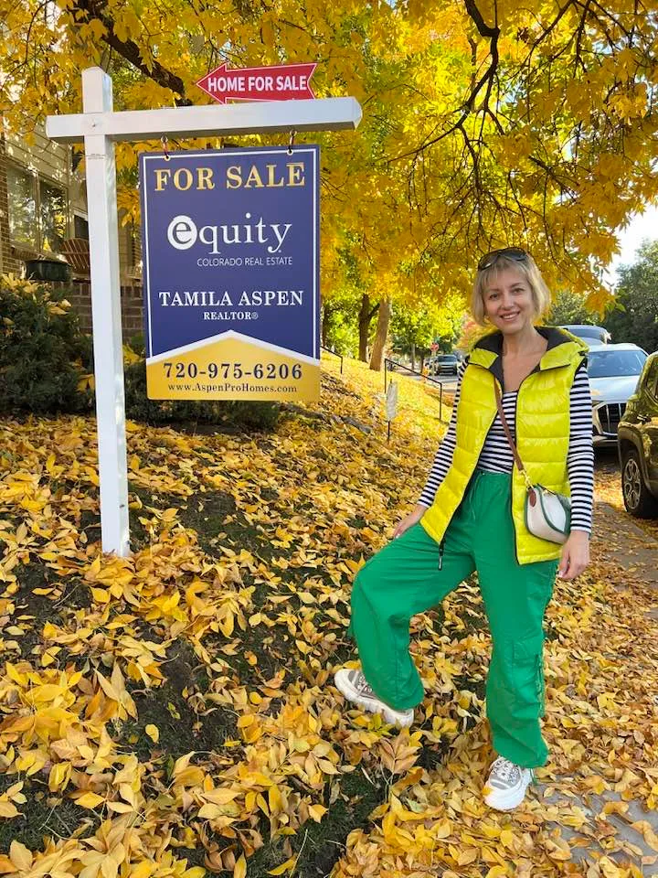 Tamila Aspen next to her Equity Colorado Real Estate For Sale sign in autumn