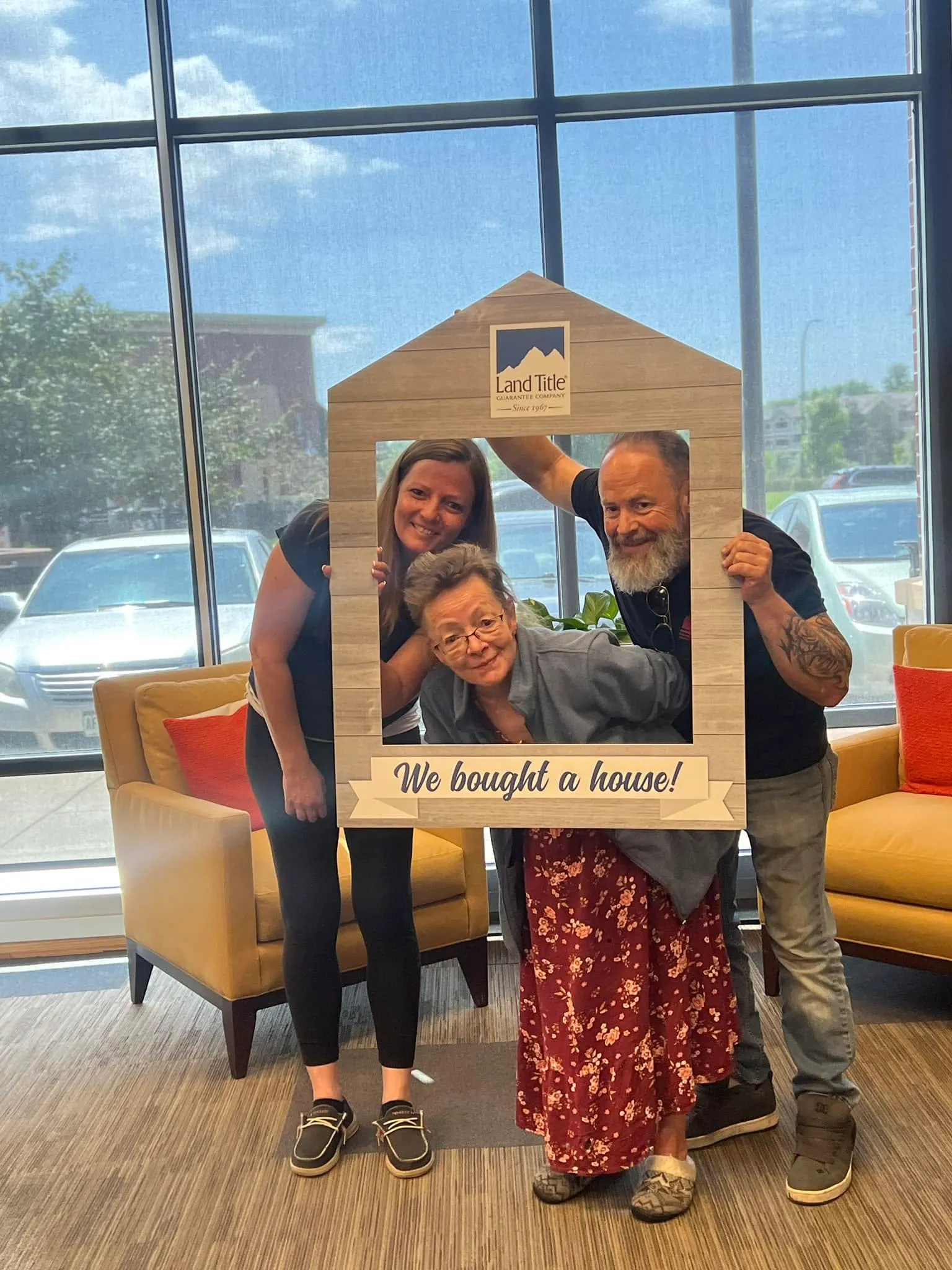 Happy couple holding a "We bought a house" frame at closing